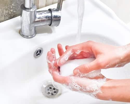 Hands washing with soap under a faucet in a sink